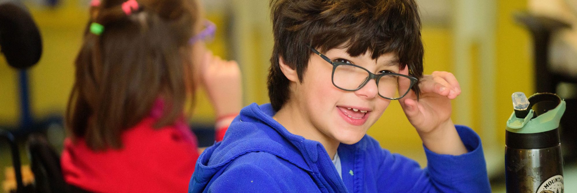 A Lower School student wearing glasses looks over his shoulder at the camera, as if he's about to say something.